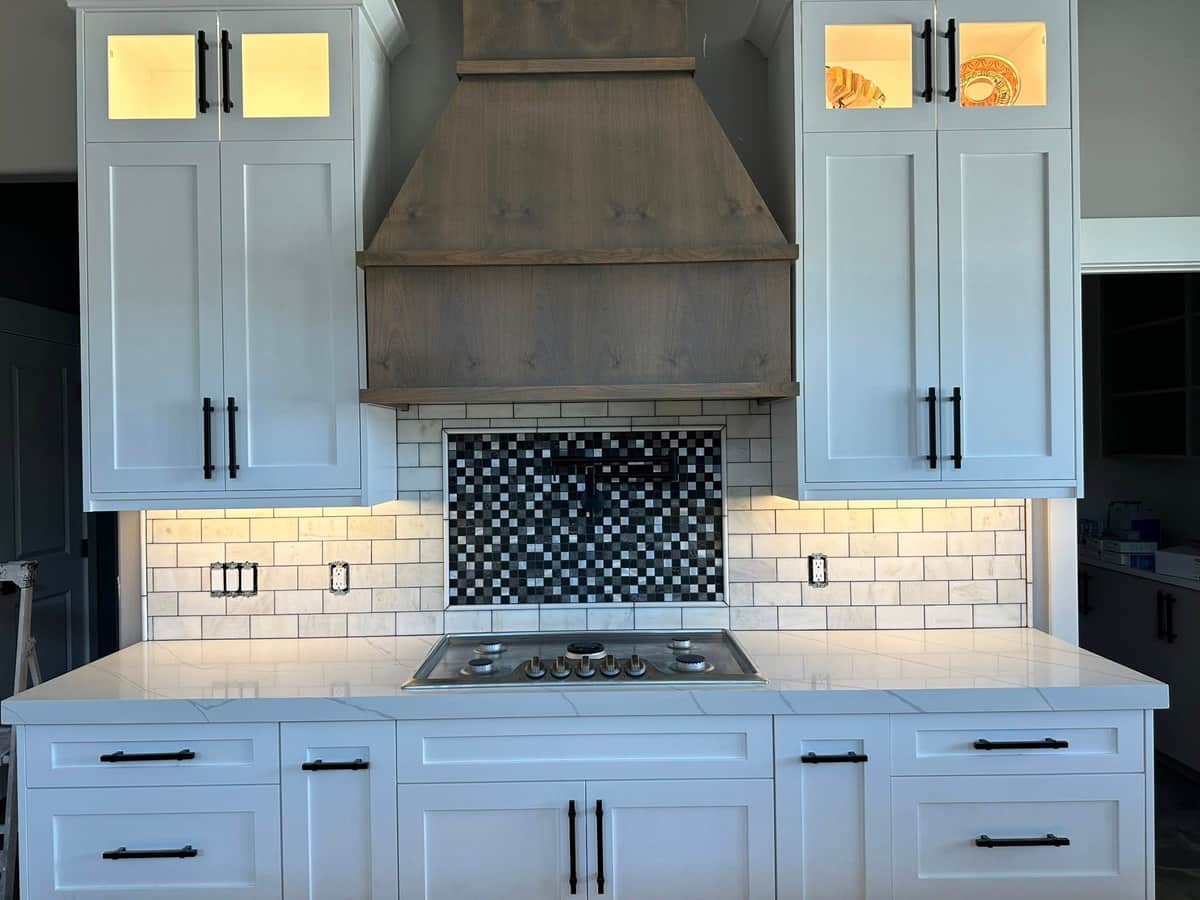 Range hood with subway tile and mosaic accent over a gas cooktop