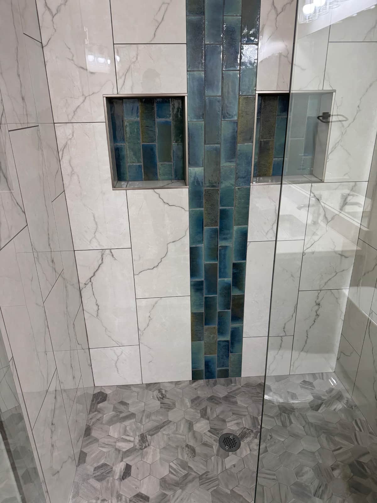 Marble shower with a blue glass accent strip